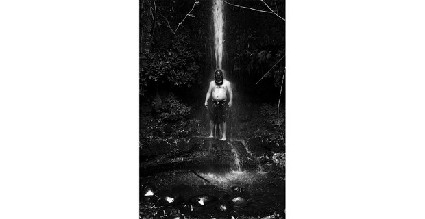 Un hombre posa bajo una cascada con la máscara utilizada en ceremonias sagradas, Río Bueno, Los Ríos, Chile, 27 de febrero de 2023. Foto: Pablo E. Poviano