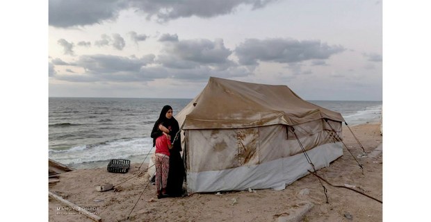 A orilla del Mediterráneo en Gaza, una madre abraza con fuerza a su hija, como si fuera su último escudo contra el miedo. Foto: Mahdy Zourob / Palestina International Broadcast